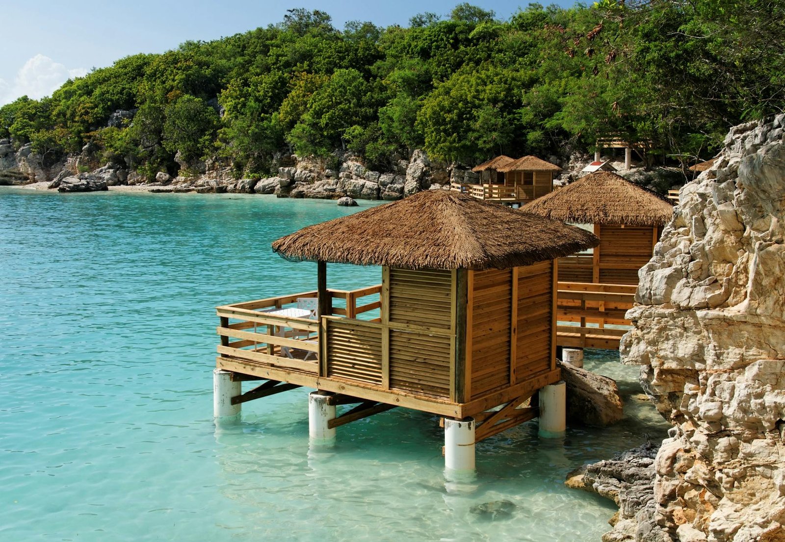 wooden thatched cottages on stilts off the coast of a tropical island
